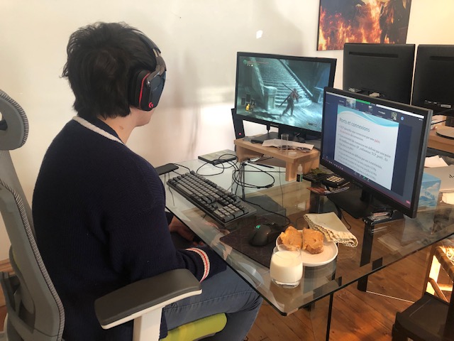 Un étudiant assistant à un cours en ligne tout en jouant sur son ordinateur